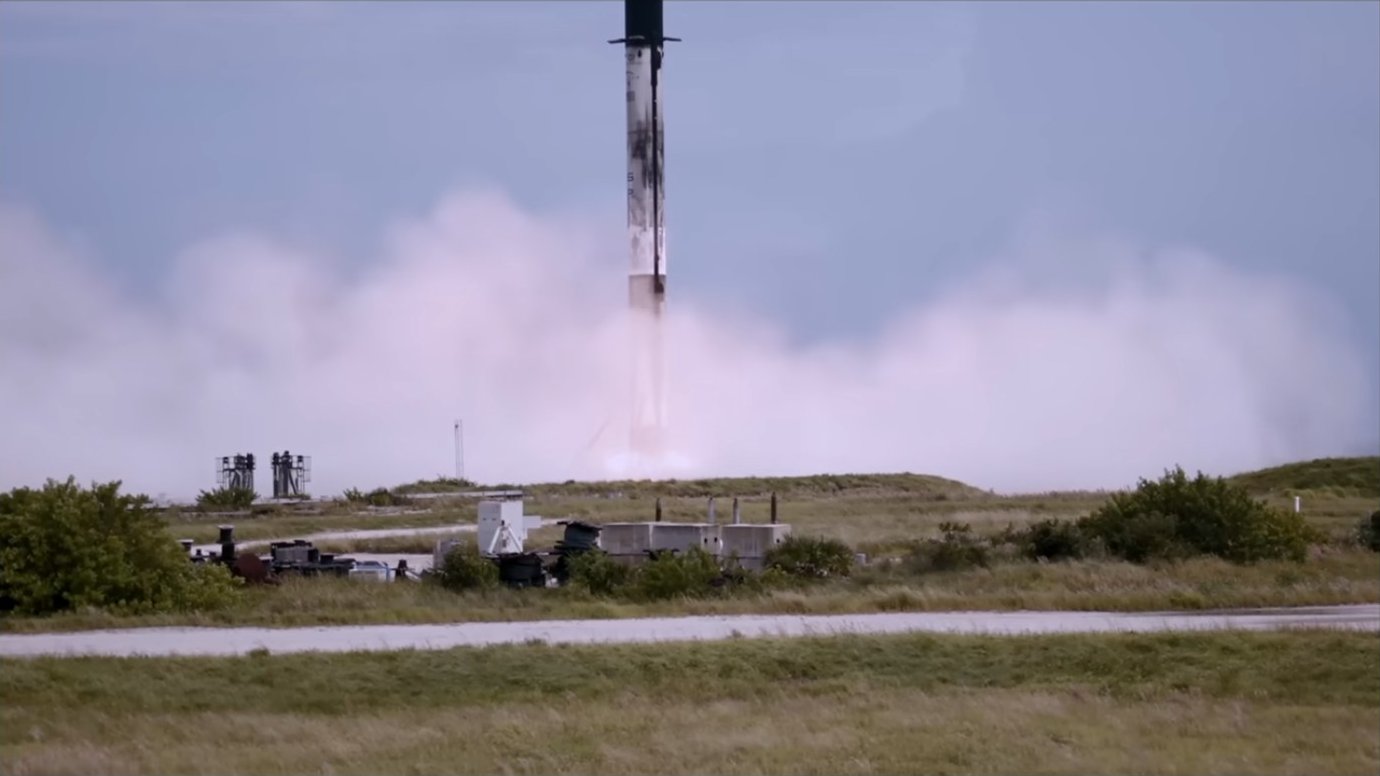 A Starship booster landing surrounded by exhaust plumes