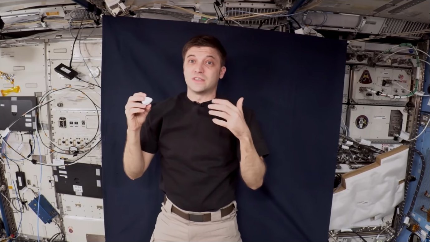 Astronaut holding a small white object inside the ISS