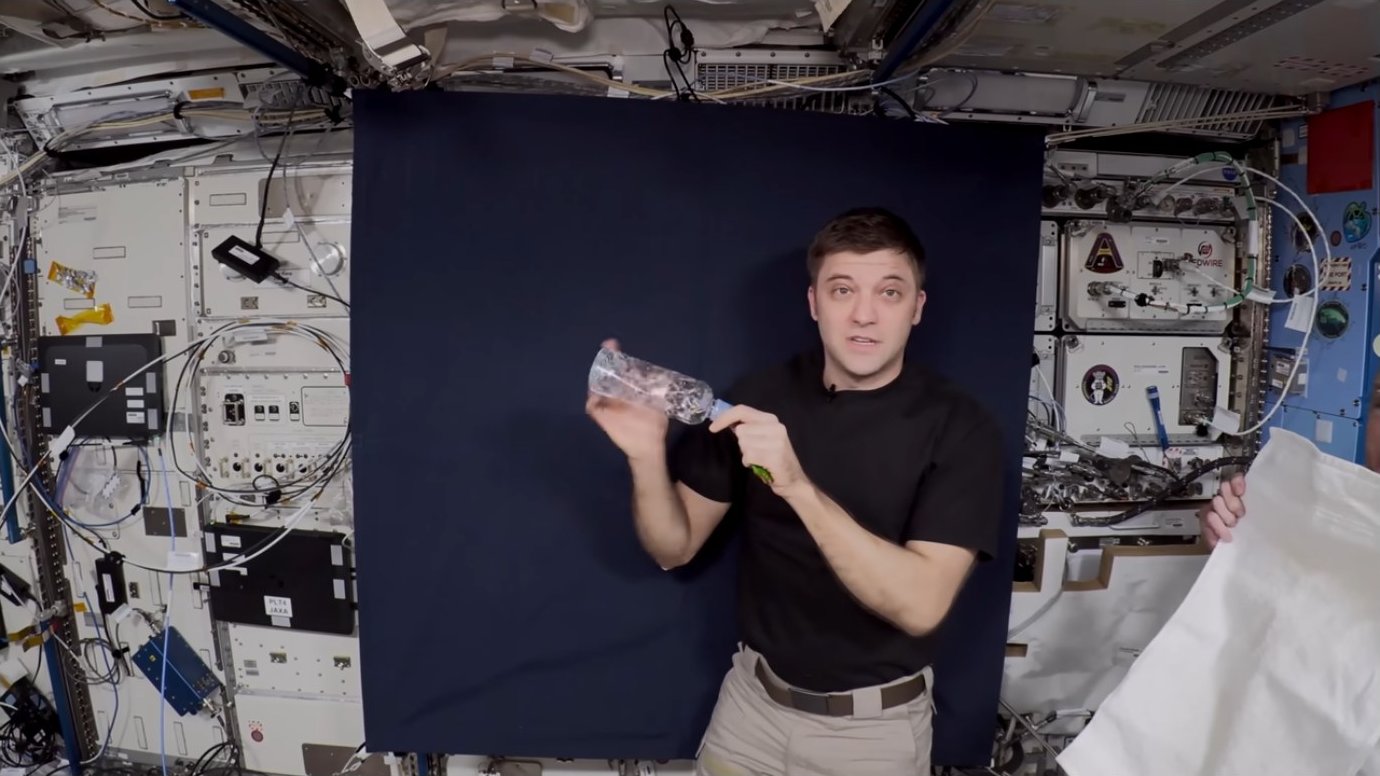 Astronaut holding a clear water bottle with visible bubbles