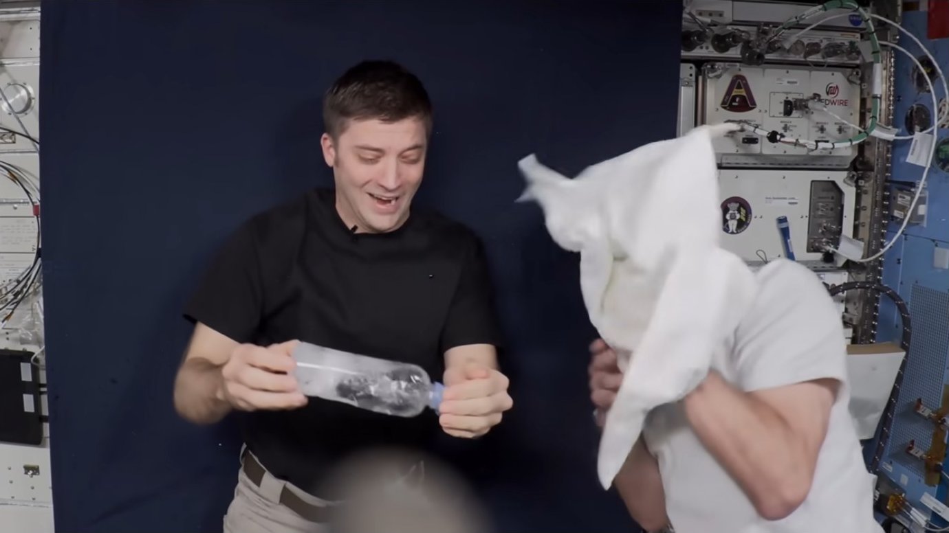 Astronaut handling the experiment while colleague holds a towel nearby