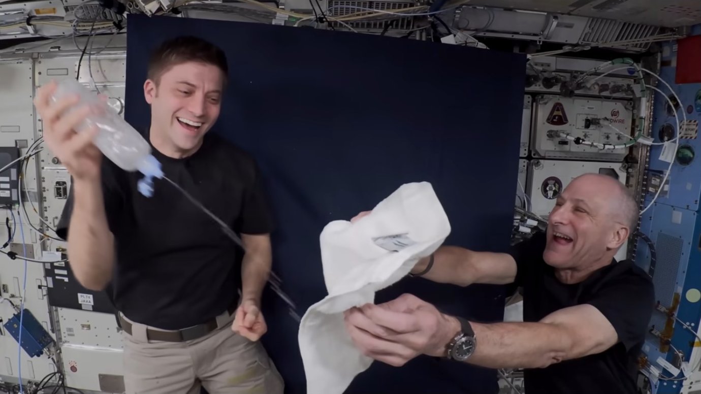 Astronauts laughing while handling the water bottle demonstration