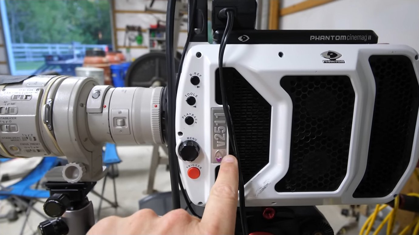 The camera setup positioned to capture supersonic phenomena, with the parabolic mirror positioned downrange to collect and focus light that has passed through the bullet's path.