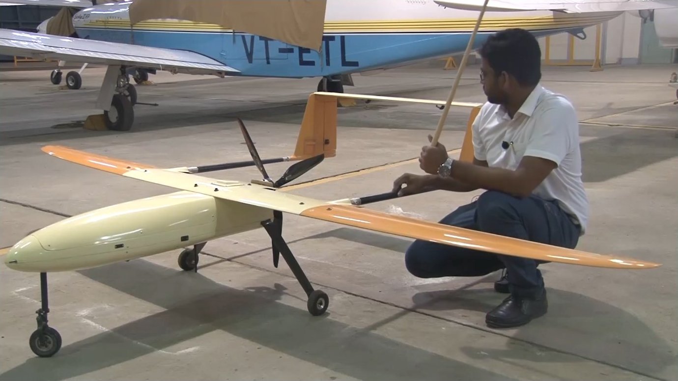 A physical UAV with a three-section wing planform illustrates the concepts discussed: a rectangular inboard section (yellow), a tapered mid-section, and an elliptical outboard panel, mounted on a twin-boom pusher configuration with T-tail.