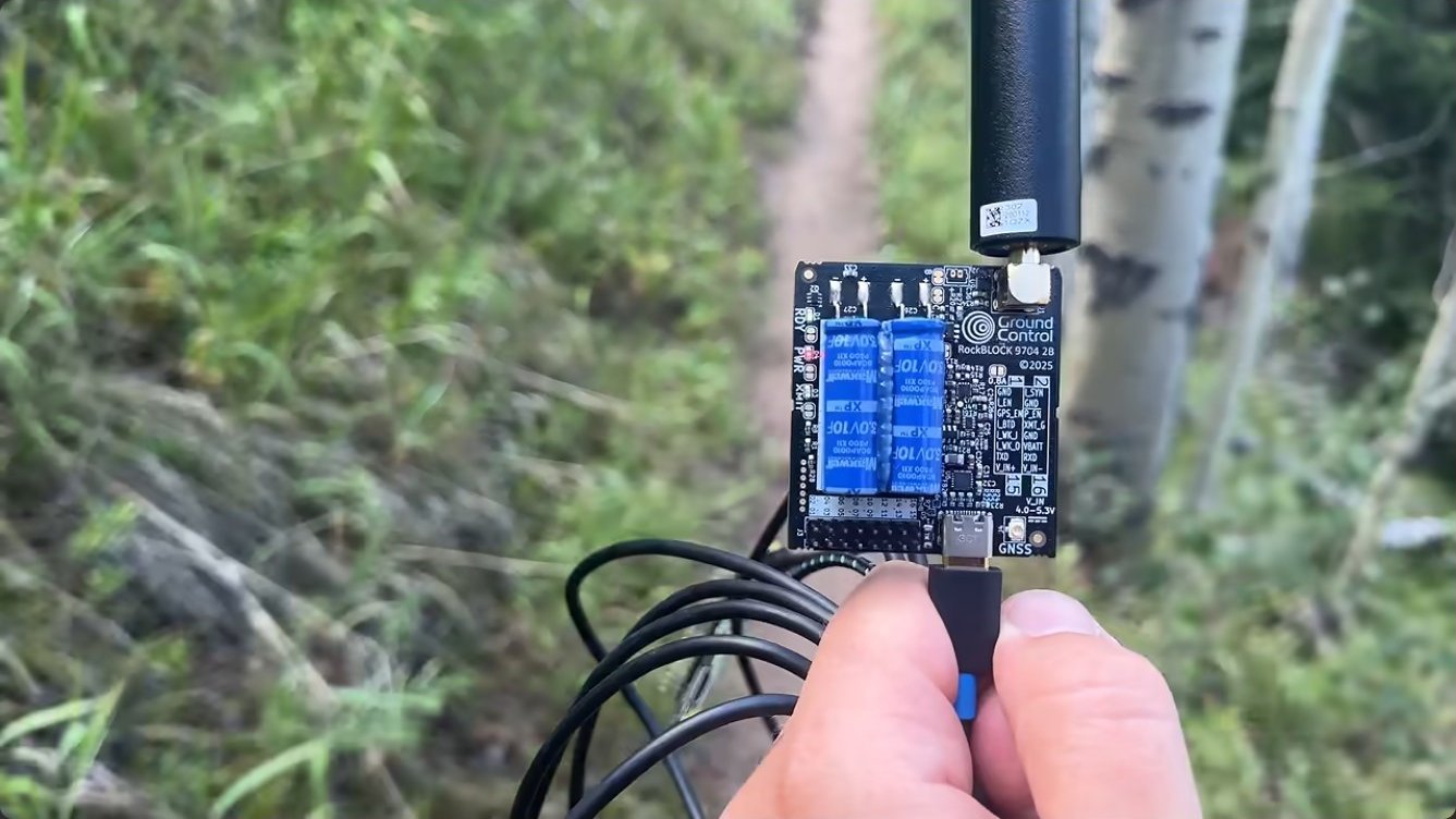 The RockBLOCK rig held up to the sky through a gap in the aspen canopy on the trail.