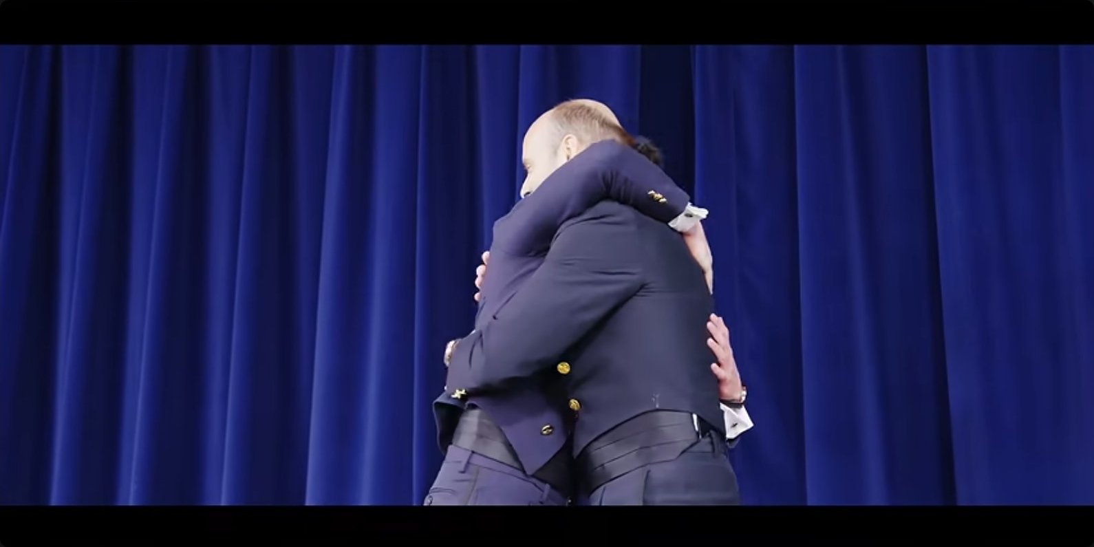 An embrace on stage at graduation — the payoff for a year of relentless work.